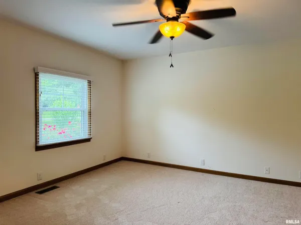 a view of an empty room with window and a ceiling fan