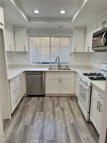 a kitchen with stainless steel appliances granite countertop white cabinets a sink and a stove