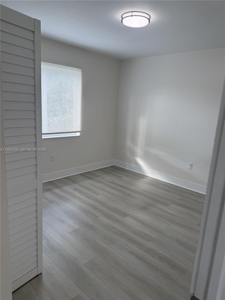 10384 Southwest 173rd Street, Unit 2 Miami, FL 33157 - Photo 6 of 12 an empty room with wooden floor and windows