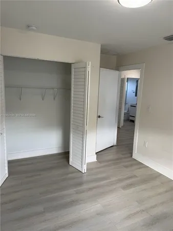 an empty room with wooden floor & closet