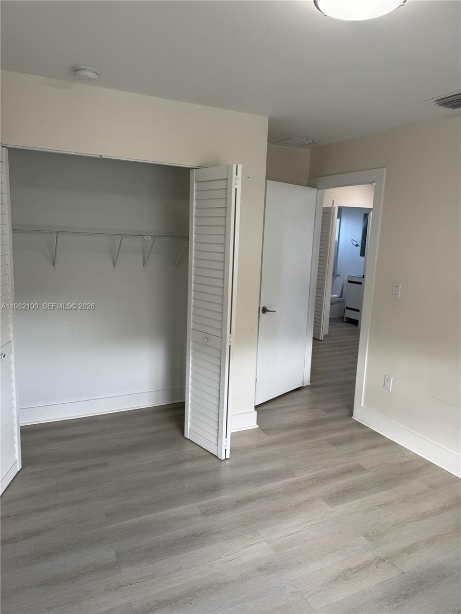 10384 Southwest 173rd Street, Unit 2 Miami, FL 33157 - Photo 9 of 12 an empty room with wooden floor & closet