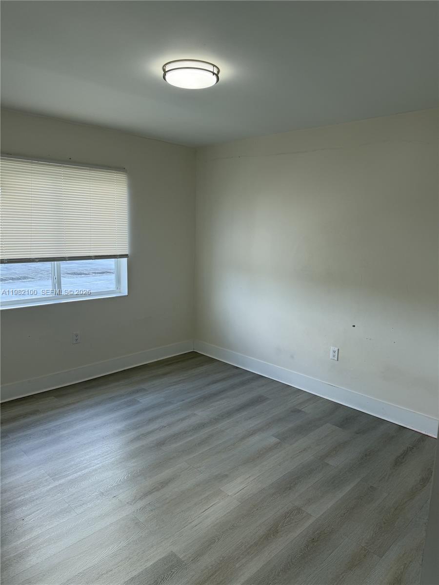 10384 Southwest 173rd Street, Unit 2 Miami, FL 33157 - Photo 10 of 12 an empty room with wooden floor and windows