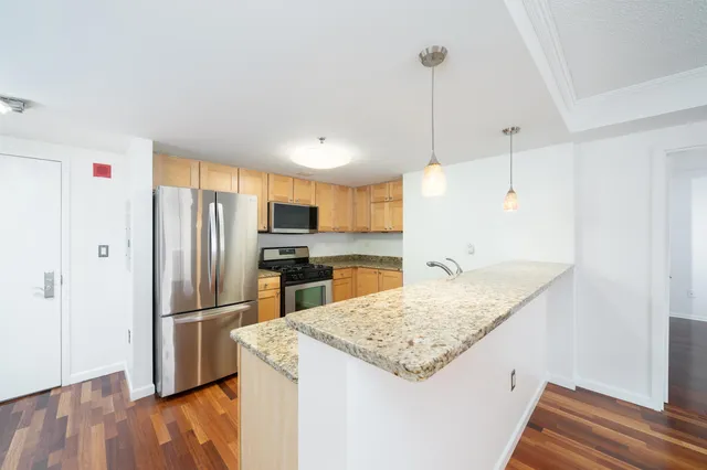 a kitchen with granite countertop kitchen island wooden floor center island and stainless steel appliances