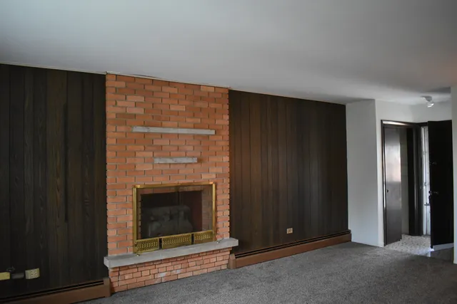 a view of an empty room with wooden floor fireplace and a window