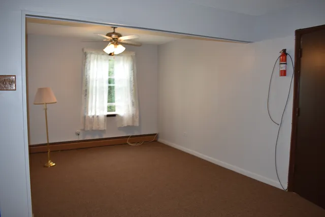 an empty room with chandelier fan and windows