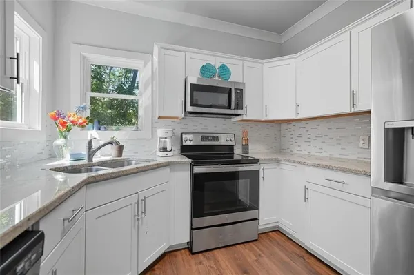a kitchen with granite countertop a sink cabinets stainless steel appliances and a window