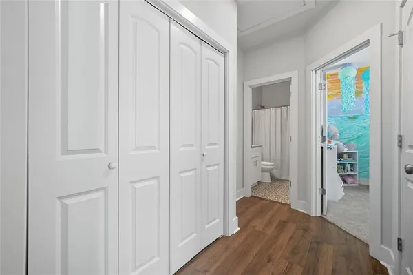 a view of a hallway with wooden floor and closet area