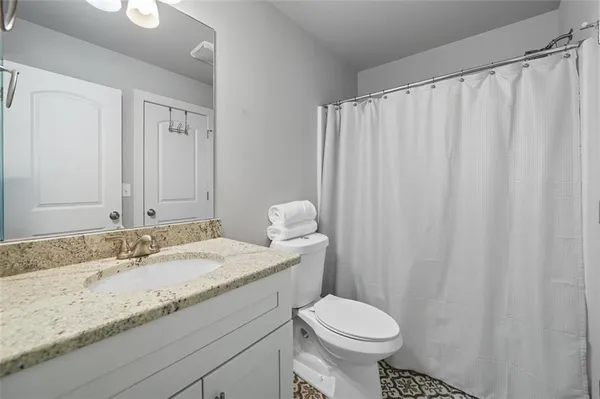 a bathroom with a granite countertop sink toilet and a mirror