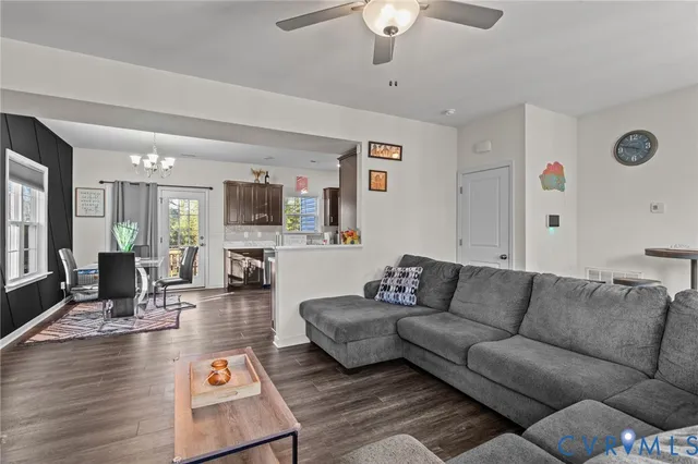 a living room with furniture kitchen view and a wooden floor