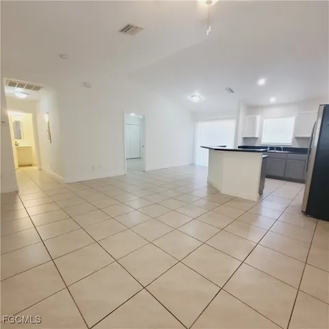 a view of a kitchen with kitchen island white cabinets and stainless steel appliances
