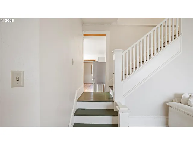 a dining room with kitchen island stainless steel appliances wooden floor dining table and chandelier
