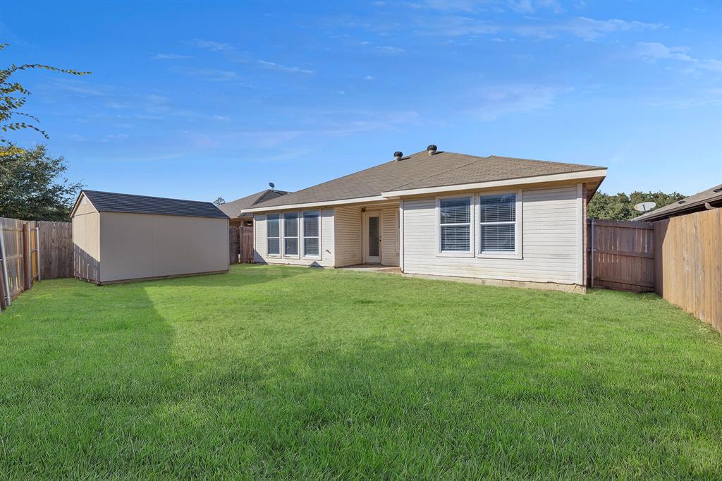 605 Clearbrook Street Azle, TX 76020 - Photo 28 of 33 Expansive backyard featuring a lush lawn, wooden privacy fencing, and a detached storage shed