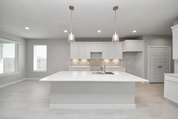 a large white kitchen with kitchen island a sink stainless steel appliances and window