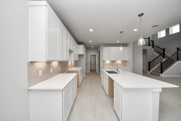 a large white kitchen with a large counter top appliances and cabinets