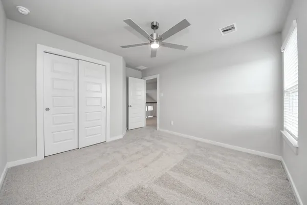 an empty room with a window and a ceiling fan