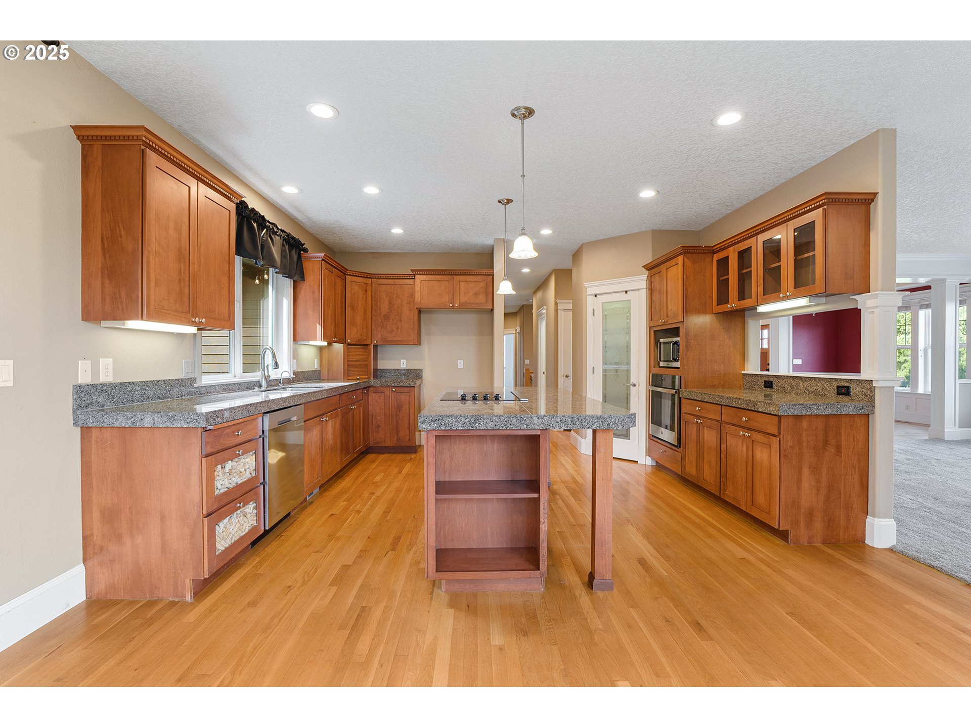 2947 Southeast Maple Place Gresham, OR 97080 - Photo 19 of 46 a kitchen with stainless steel appliances kitchen island granite countertop a stove top oven a sink dishwasher a dining table and chairs with wooden floor