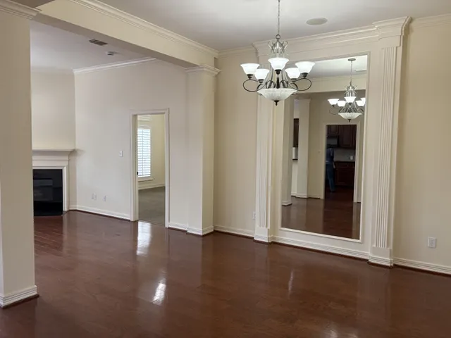 a view of a chandelier in big room with wooden floor and chandelier