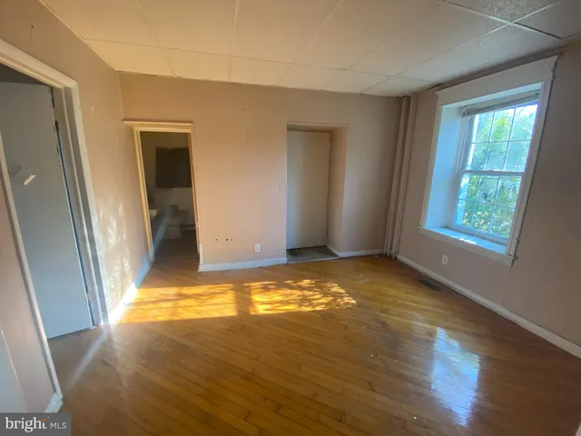 a view of an empty room with window and a kitchen