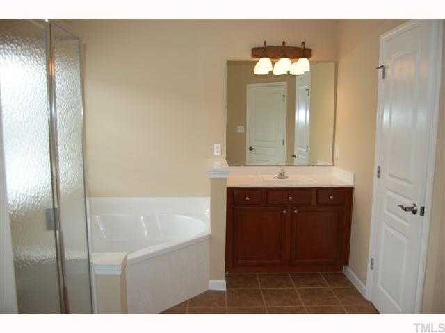 8620 Churchdown Court Raleigh, NC 27613 - Photo 8 of 12 a bathroom with a sink a mirror and a shower