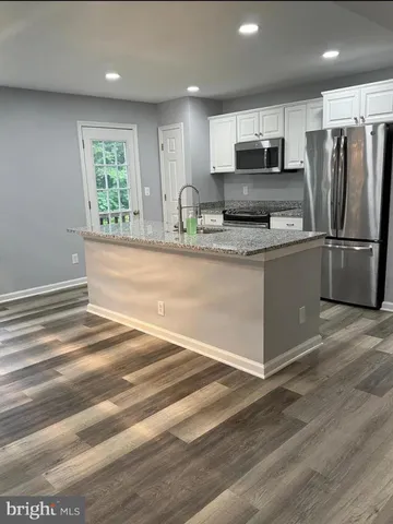 a large kitchen with stainless steel appliances granite countertop a refrigerator a stove a sink and a granite counter tops