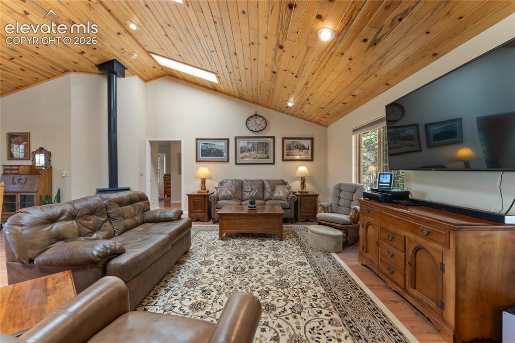 657 Spring Valley Drive Divide, CO 80814 - Photo 7 of 43 Vaulted wood-paneled ceiling with skylights and recessed lighting, featuring a prominent stand-alone stove with black stovepipe, light-toned wall finishes, and wood-finish flooring