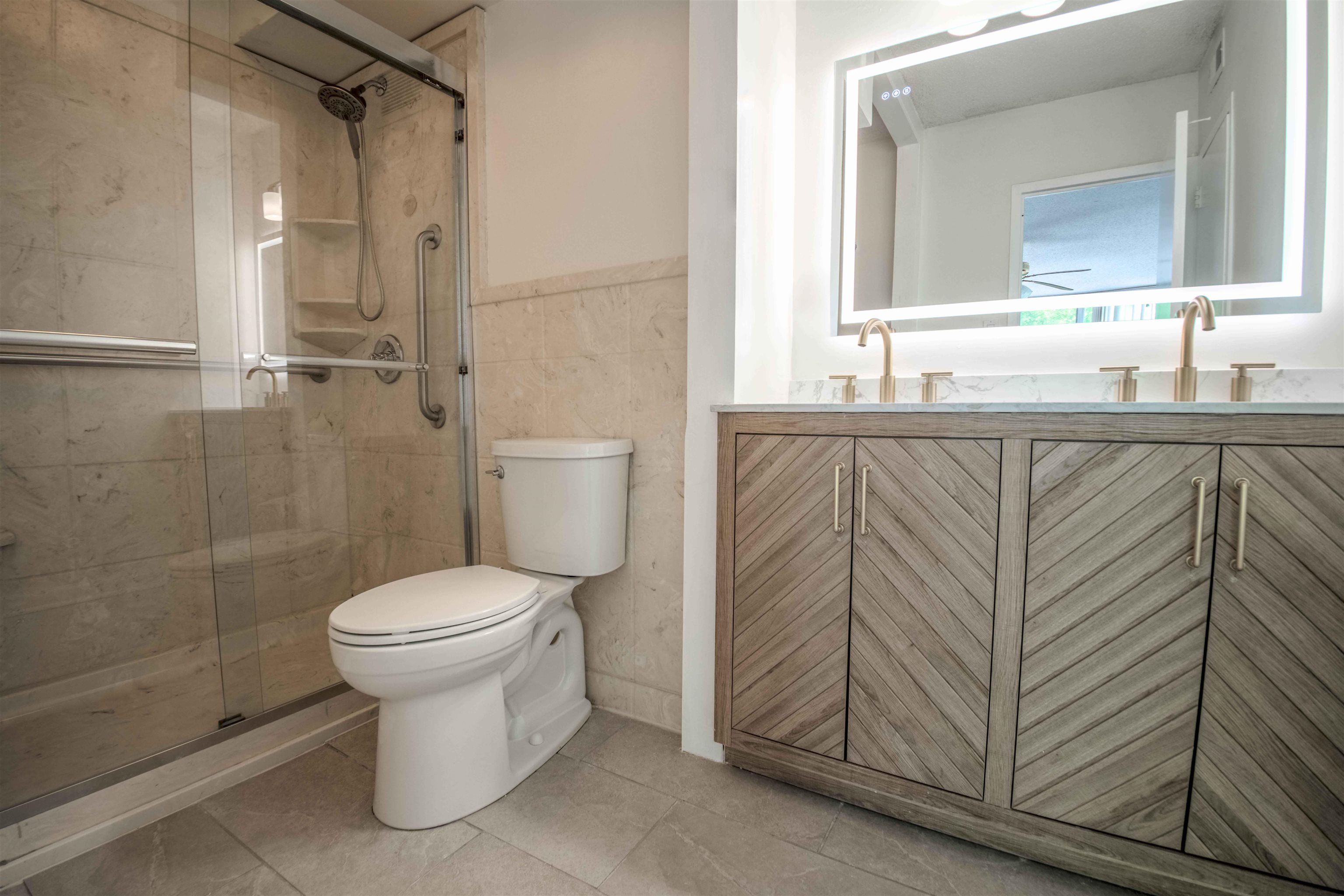 3080 Walnut Grove Road, Unit 306 Memphis, TN 38111 - Photo 14 of 18 Contemporary bathroom featuring a double vanity with textured wood-finish cabinetry, a large illuminated mirror, and a glass-enclosed shower