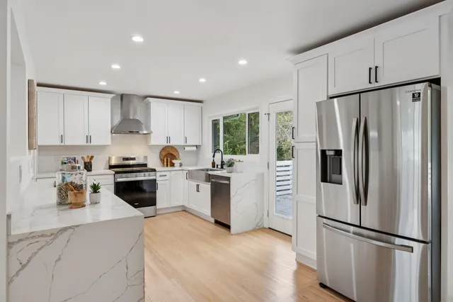 a kitchen with granite countertop a refrigerator a sink dishwasher a stove top oven a refrigerator and cabinets