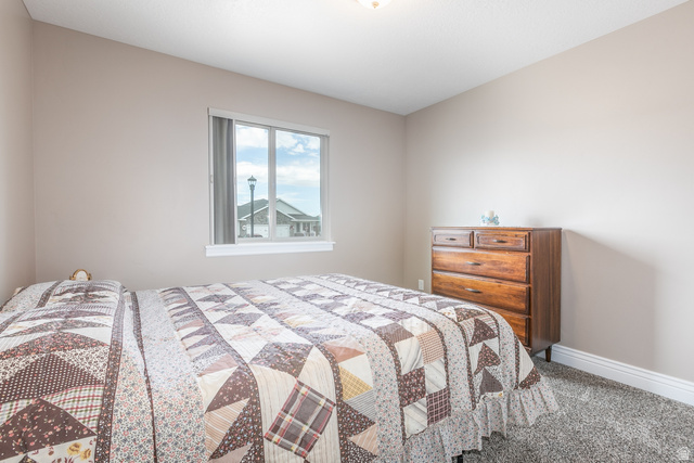 1228 North Providence Way Tooele, UT 84074 - Photo 18 of 28 Bedroom featuring a window with white trim, light-colored walls, textured carpeting, and white baseboards