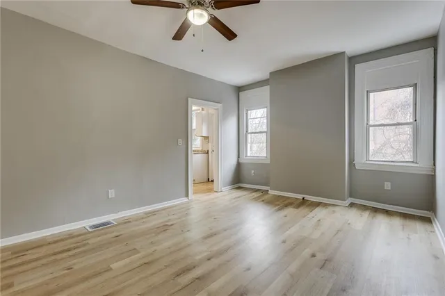 a view of an empty room with window and wooden floor