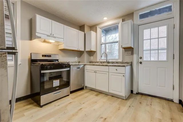 a kitchen with cabinets stainless steel appliances and a window