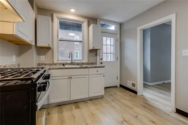 a kitchen with stainless steel appliances granite countertop a stove a sink and white cabinets