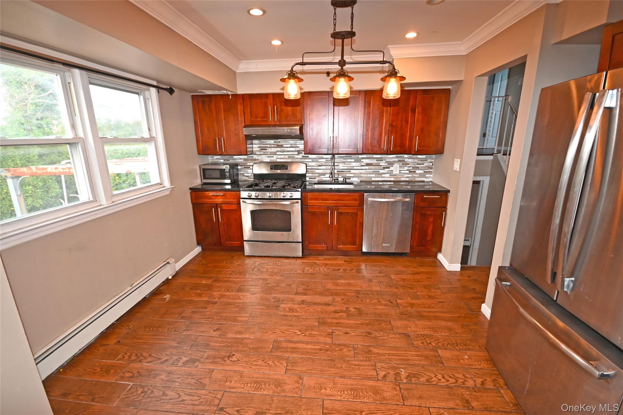 89 Osborne Road West Hempstead, NY 11552 - Photo 32 of 50 Kitchen with appliances with stainless steel finishes, a baseboard radiator, tasteful backsplash, hanging light fixtures, and dark wood finished floors