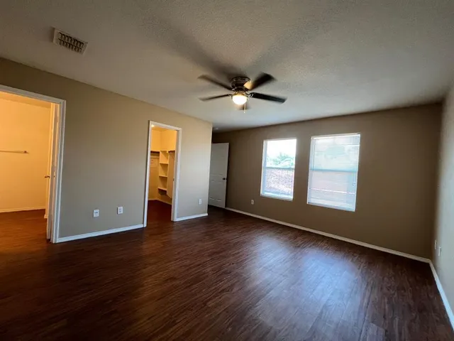 a view of an empty room with window and wooden floor