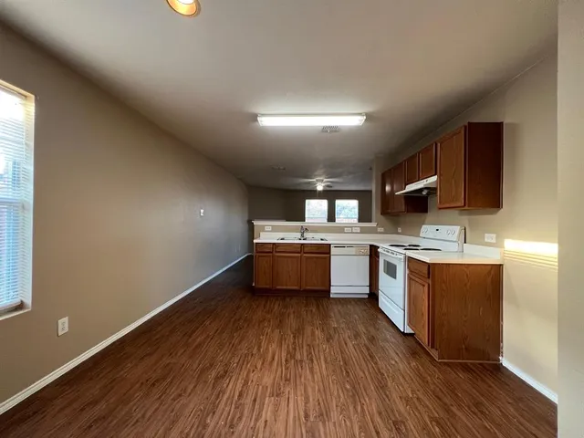 a kitchen with stainless steel appliances wooden floors and a view of living room