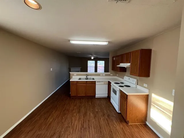a kitchen with stainless steel appliances granite countertop a stove a sink dishwasher and a refrigerator with wooden floor