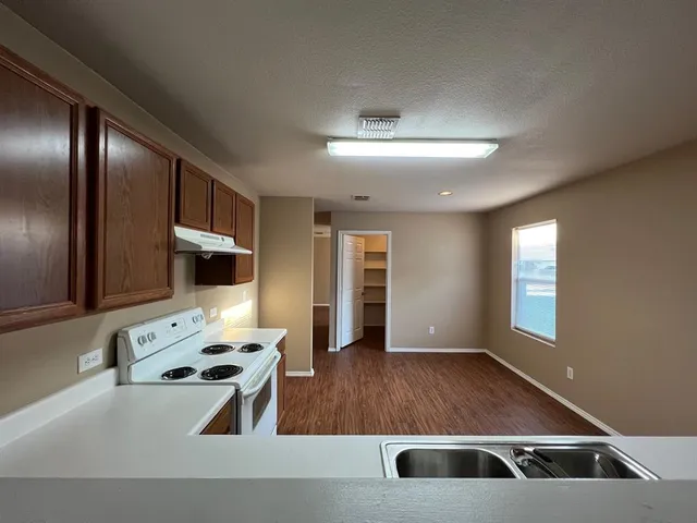 a living room with stainless steel appliances kitchen island granite countertop a refrigerator and a stove top oven