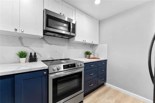 a kitchen with stainless steel appliances granite countertop a refrigerator a stove and a sink with wooden floor