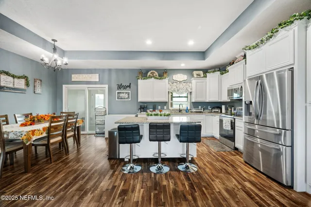 a kitchen with stainless steel appliances a stove a sink dishwasher a refrigerator with white cabinets and wooden floor