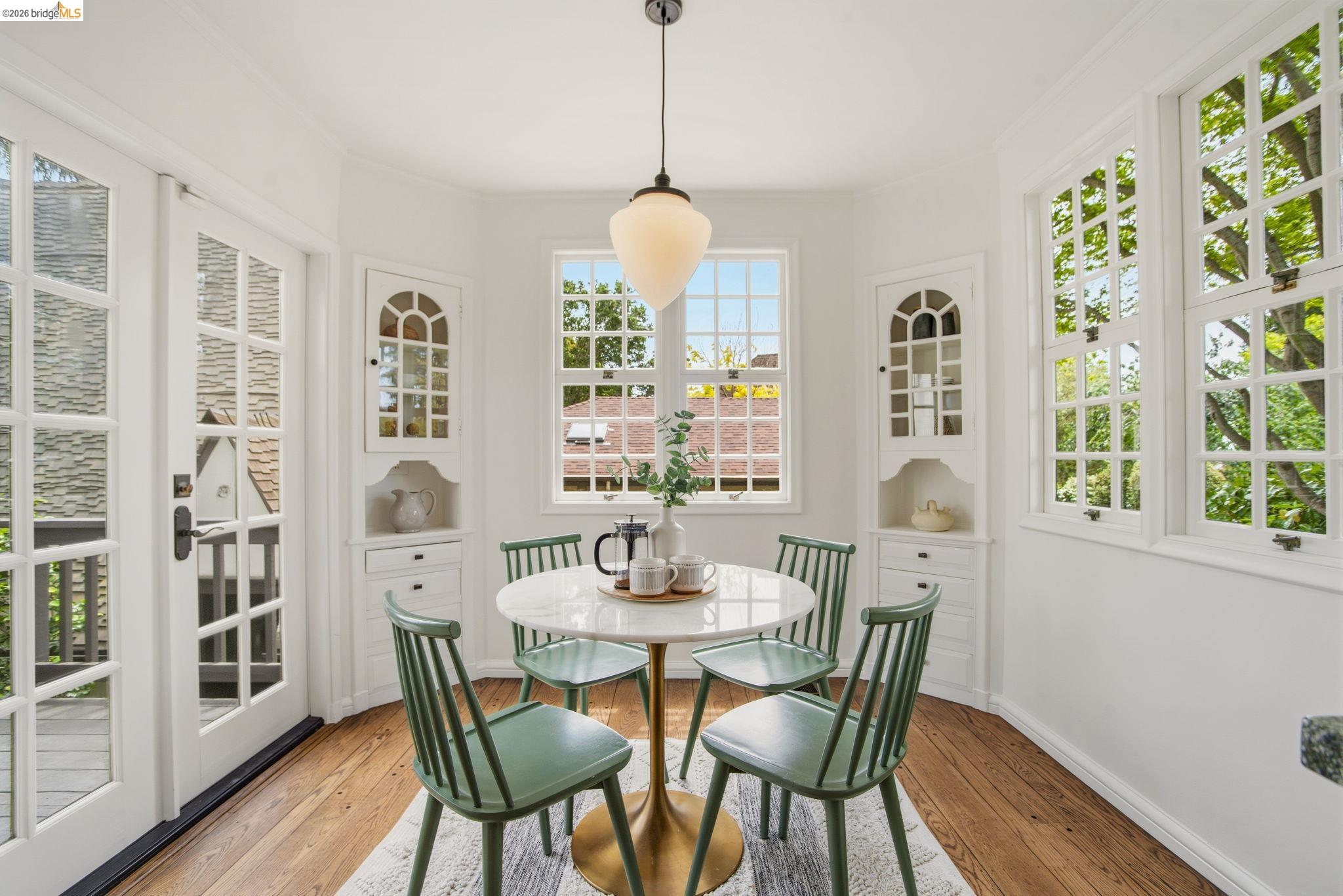 1087 Hubert Road Oakland, CA 94610 - Photo 18 of 67 Bright dining area featuring hardwood flooring, multiple grid-pattern windows, a French door, and built-in corner cabinetry