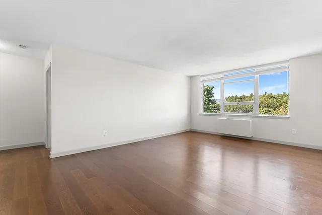 an empty room with wooden floor and window