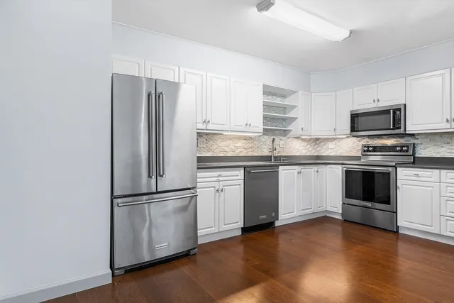 a kitchen with a refrigerator stove and wooden floor