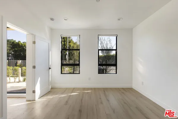 a view of an empty room with glass door and wooden floor