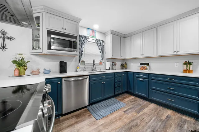 a kitchen with stainless steel appliances granite countertop a sink a stove a microwave cabinets and a dining table