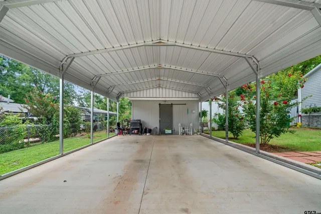 a view of a patio with table and chairs under an umbrella with a large tree