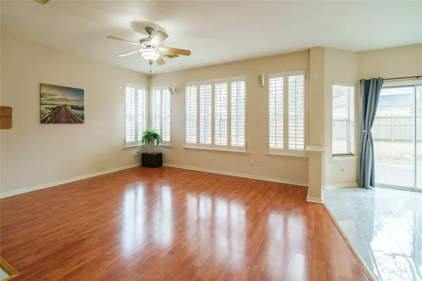 a view of an empty room with a window and wooden floor