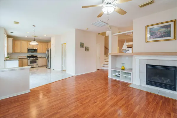 a view of a kitchen and an empty room with wooden floor
