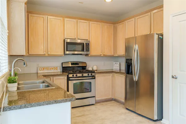 a kitchen with stainless steel appliances granite countertop a refrigerator stove and sink