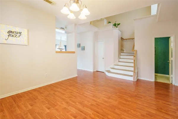 a view of an empty room with wooden floor and a kitchen