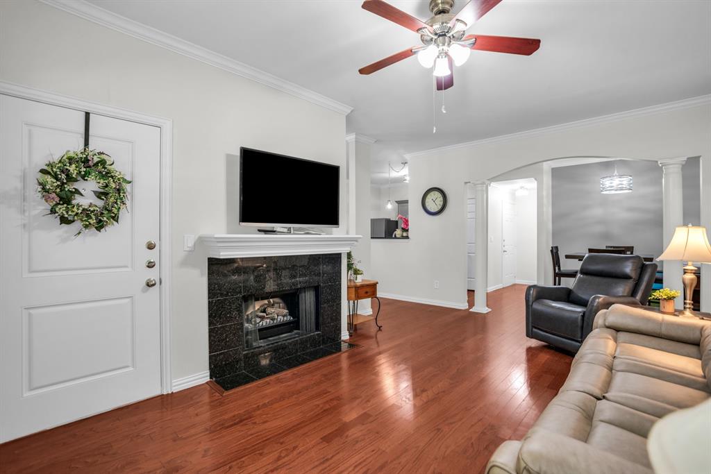 2524 Preston Road, Unit 808 Plano, TX 75093 - Photo 11 of 31 Living area featuring rich wood-finish flooring, a ceiling fan with integrated lighting, and a dark tile fireplace with a white mantel