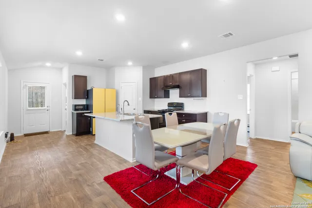 a living room with furniture a kitchen view and a wooden floor